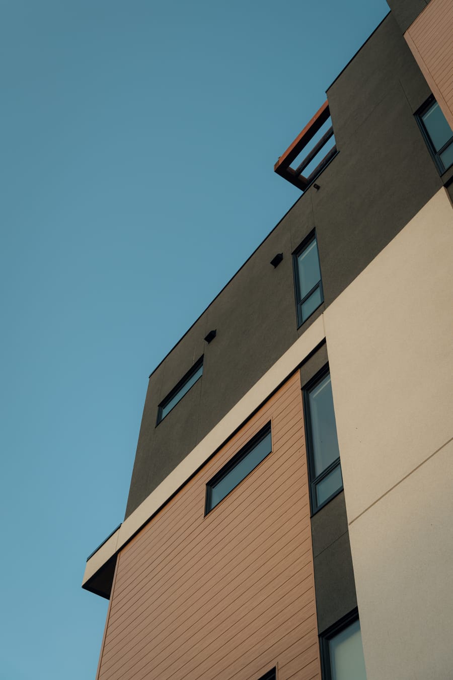Dark steel and timber corner of the building against a clear blue sky