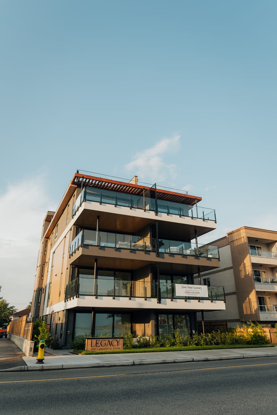 Legacy on Lakeshore, a four-storey lakefront residence in Penticton, seen from the street with its glass balconies and rooftop terrace