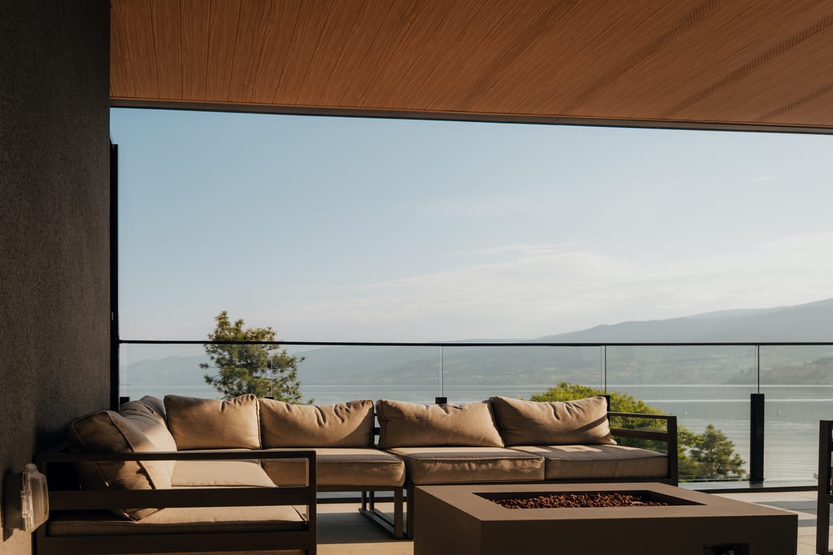 Rooftop lounge at Legacy on Lakeshore with a fire table and Okanagan Lake beyond the glass rail